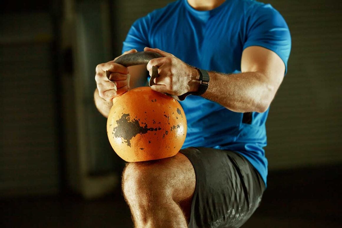 Person holding a kettlebell by the horns in a forward lunge position — a fundamental movement pattern for beginners over 50