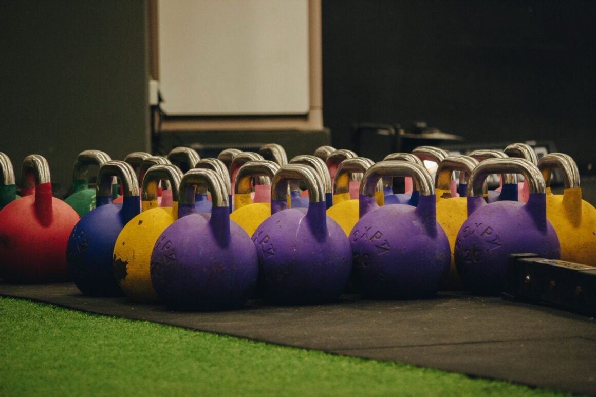 Colorful competition kettlebells lined up on turf before a kettlebell training session