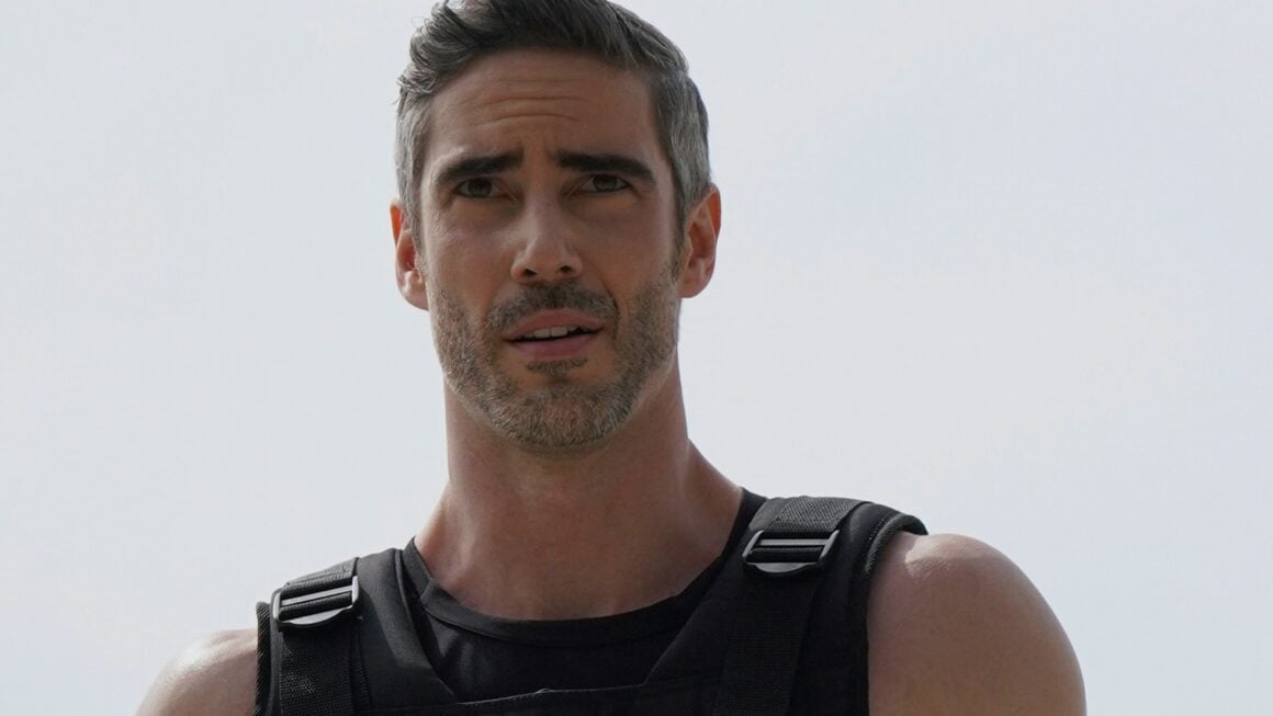 Man wearing a black weighted vest with adjustable shoulder straps and buckles outdoors