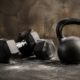 A pair of dumbbells and a kettlebell on a chalk-dusted gym floor