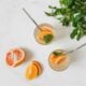 A refreshing drink in a clear glass, surrounded by colourful fruits and herbs.