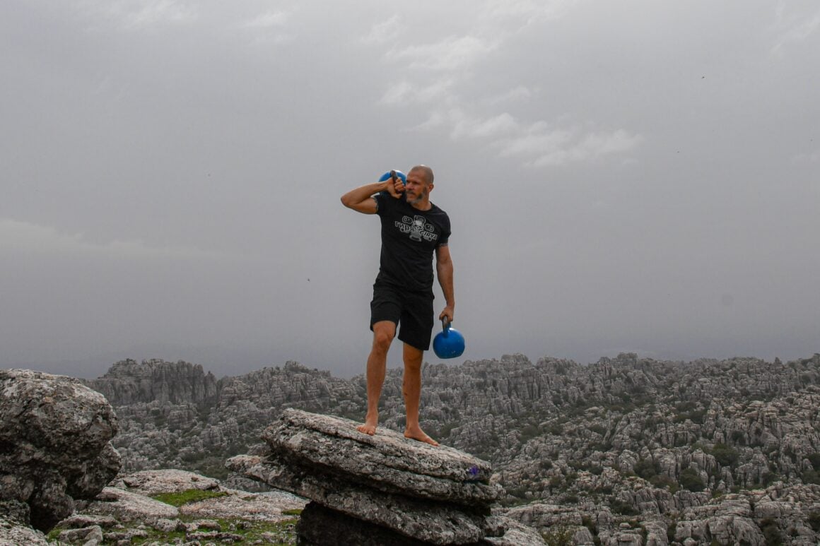 Taco Fleur carrying two competition kettlebells across the rocks of El Torcal de Antequera